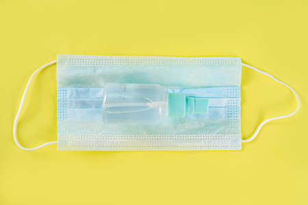 Protection against  virus concept. Hand sanitizer spray and face surgical masks . On trendy yellow...
