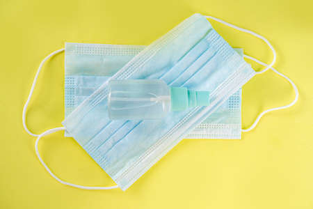 Protection against  virus concept. Hand sanitizer spray and face surgical masks . On trendy yellow...