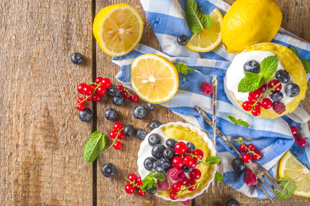 Lemon Mug Cake. Summer sweet dessert in Microwave. Lemon Mug Pies with fresh berries and whipped cream, on wooden backgroundの写真素材