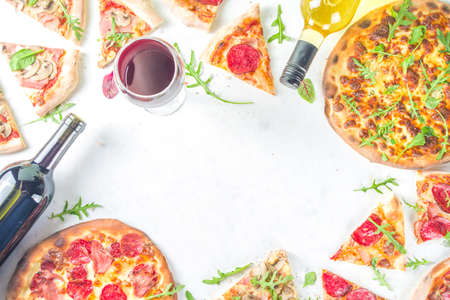 Pizza party concept. Set of pizzas with various fillings, Pieces of different pizza, glass and bottle with wine. Flatlay top view copy space on white backgroundの写真素材