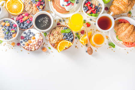 Various breakfast food concept. Traditional healthy breakfast foods and drinks - oats, granola, yoghurt, smoothie bowl, toasts, cereal, growing, coffee and tea cup, orange juice, with fruit, berryの写真素材