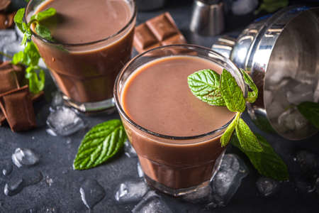 Iced Chocolate cocktail. Summer refreshment drinks. Chilled iced chocolate coco drink, latte coffee. With ice, mint and chocolate slices on dark background copy spaceの写真素材