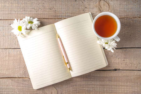 Cozy breakfast in spring or early autumn tea with bouquet of Chamomile daisy flowers and note book....