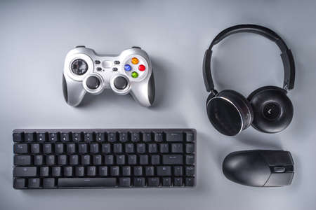 Gaming and gamer devices concept. Gamer work table space background, top view. Keyboard, mouse, gamepad joystick, mouse pad and headphones. on gray table background above with copy space for textの写真素材