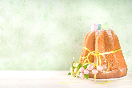 Easter sweets and decorations background, Sweet easter cake panettone with colorful painted eggs, spring grass and decor, copy space for textの写真素材