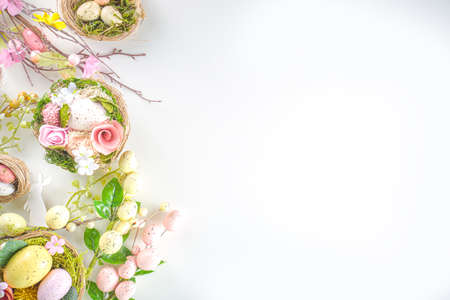 Easter greeting card background. Spring tree decor branches with colorful eggs, flowers and leaves on white background copy space for your textの写真素材