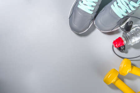 Woman athlete's set with dumbbells and bottle of water headphones. Sport and fitness concept on gray background top view copy space for textの写真素材