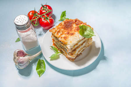 Mediterranean food, Italian traditional lasagna pasta, with bolognese, bechamel and cheese. On trendy breght light blue background with hard light and dark shadows copy spaceの写真素材