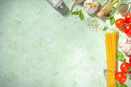 Mediterranean food cooking background, fresh tomatoes, basil, olive oil and garlic on light green background copy space top viewの写真素材