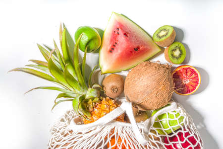 Summer vegetarian and sustainable shopping concept, shopping bag full of fresh tropical fruits, on...