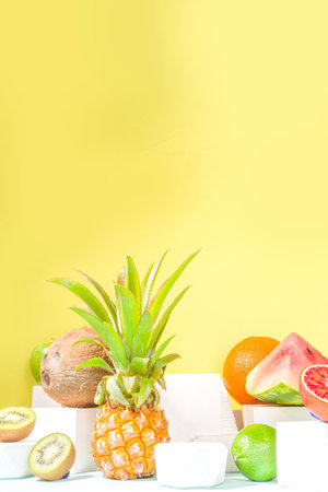 Summer composition, Various tropical fruits, on modern bright yellow background with podiums, copy space. Holiday and vacation, healthy food concept copy spaceの写真素材