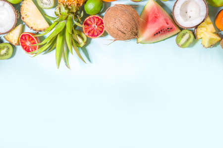 Summer vitamin food concept, various fruit and berries background - watermelon pineapple apples kiwi coconut orange lime creative flat lay on light blue background top view copy spaceの写真素材