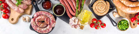 Set of different raw beef, pork and chicken meat sausages on cooking table with spices, sauces and...