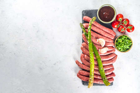 Set of different raw beef, pork and chicken meat sausages on cooking table with spices, sauces and...