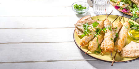 Chicken shish kebabs on wooden skewers sticks top view. Traditional Mediterranean dish kebaps with ground chicken meat, sunny white wooden background copy spaceの写真素材