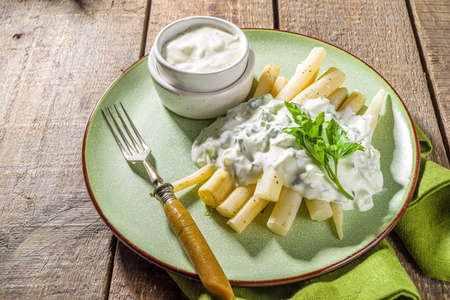 Cooked Polish East European black asparagus (black carrot) skorzonera, boiled with spices and tzatziki sauce. On a wooden table copy spaceの写真素材