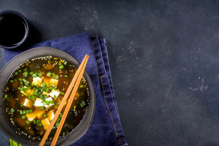 Portioned bowl miso soup, with wakame seaweed, tofu and chopsticks on black background copy spaceの写真素材