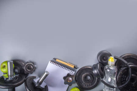 Mens Fitness background with dark Iron dumbbells, sneakers, headphones, gren apples and water bottle. On gray background top view copy spaceの写真素材