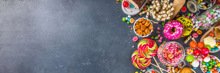 Selection of colorful sweets. Set of various candies, chocolates, donuts, cookies, lollipops, ice cream top view on black concrete backgroundの写真素材
