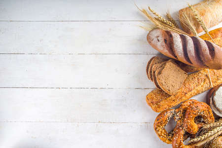 Assortment of various delicious freshly baked bread, on white background top view copy space
