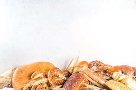 Assortment of various delicious freshly baked bread, on white background top view copy space