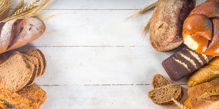 Assortment of various delicious freshly baked bread, on white background top view copy space