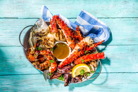 Assortment various barbecue Mediterranean grill food - fish, octopus, shrimp, crab, seafood, mussels, summer diet bbq party fest, with kebab, sauces, light blue sunne wooden backgroundの写真素材