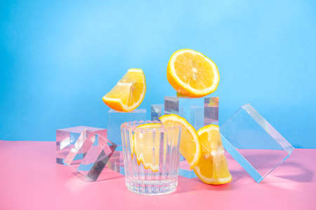 Summer bright lemonade on colorful blue pink background with glass pedestals podiums with fresh fruits, copy spaceの写真素材