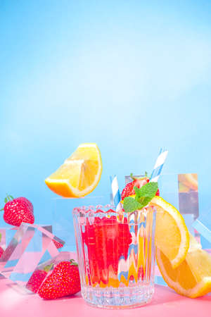 Summer bright lemonade on colorful blue pink background with glass pedestals podiums with fresh fruits, copy spaceの写真素材
