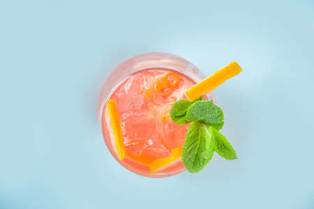 One glass with summer cold drink lemonade with grapefruit pieces, ice and mint