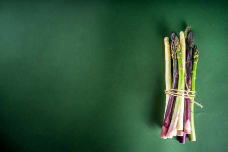 Fresh raw organic asparagus bunch, purple, green and white vegetable on dark green backgroundの写真素材