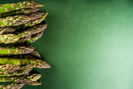 Fresh raw organic asparagus bunch, purple, green and white vegetable on dark green backgroundの写真素材