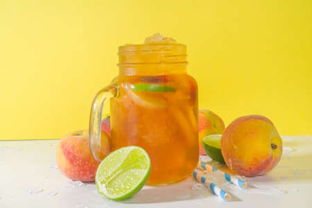 Summer cold refreshment drink, traditional iced peach tea cocktail with crushed ice, peach slices...