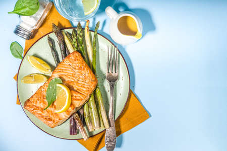 Vegan healthy food, keto diet recipe, Baked grilled salmon fish steak with green, white, purple asparagus, light blue sun lighted background top view copy spaceの写真素材