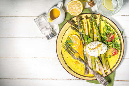 Healthy food, baked grilled asparagus, poached egg and hollandaise sauce on white wooden background copy space top viewの写真素材