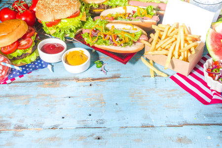 Fourth of July, Memorial Day, USA Independence Day concept. Patriotic, American traditional food. Picnic party with watermelon, burgers, hot dogs, drinks, blue wooden outdoor table backgroundの写真素材