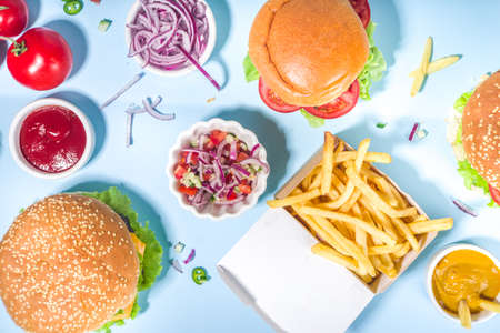 Fastfood, burger party concept. Various delicious burgers set with french fries and sauces on bright...