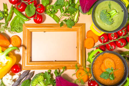 Set of various colorful vegetable soups.Variety of classic vegetable cream soups, in small portioned pots - asparagus, spinach, broccoli, green peas, tomato, carrot. Beige warm colored background copy space top viewの写真素材