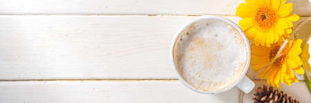 Cozy autumn background with hot coffee latte mug, with notepad, pumpkins, gerbera flowers, fall leaves. Thanksgiving day, Halloween greeting card, festive compositionの写真素材