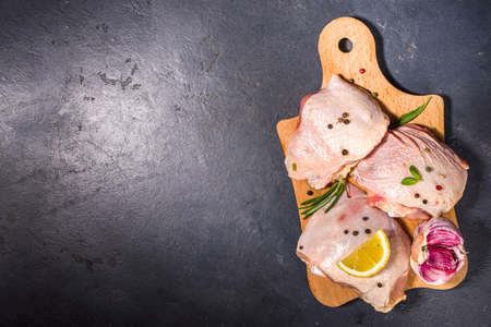 Raw uncooked chicken legs, with spices and herbs for cooking, black table background top view copy spaceの写真素材