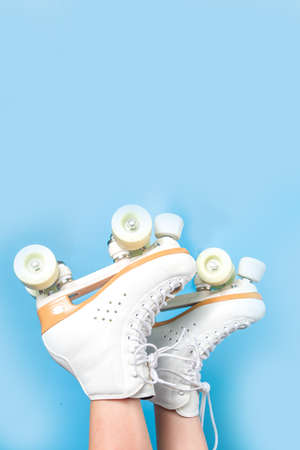 Cute attractive cheerful caucasian roller girl with quads skates, bright blue color background