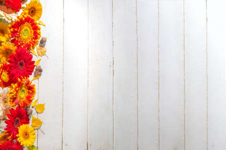 Autumn Seasonal Flowers and Decor Background. White wooden table with pumpkins, red, yellow and...