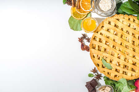 Autumn cooking baking background with sweet apple pie. Traditional american apple pie with fresh apples, cinnamon, spices, baking ingredients, top view copy space on white backgroundの写真素材