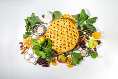 Autumn cooking baking background with sweet apple pie. Traditional american apple pie with fresh apples, cinnamon, spices, baking ingredients, top view copy space on white backgroundの写真素材