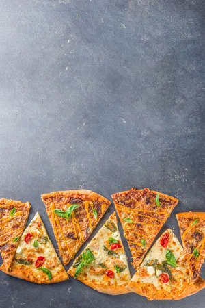 Various italian american traditional pizza slices. Slices of delicious pizza on dark gray concrete background, top view flatlayの写真素材