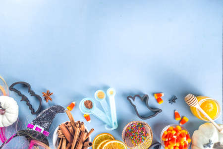 Halloween Gingerbread Cookies cooking background. Autumn holiday baking concept, ingredients, spices, halloween symbol cookie cutters - pumpkin, ghost, bat, witch hat, top view blue table copy spaceの写真素材