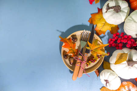 Thanksgiving day table setting, cutlery (plate, knife, fork) and napkin with decoration on blue table, top view copy spaceの写真素材