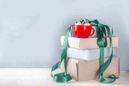 Big stack of Christmas gifts with hot chocolate, stay on it like pedestal, cozy pastel colored craft...