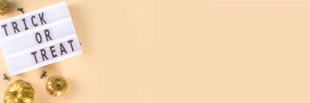 Trick or treat background, Simple Halloween greeting card, party invitation abstract flatlay with golden colored pumpkins, stars, spiders, on beige yellow background copy space top viewの写真素材