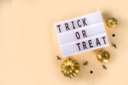 Trick or treat background, Simple Halloween greeting card, party invitation abstract flatlay with golden colored pumpkins, stars, spiders, on beige yellow background copy space top viewの写真素材